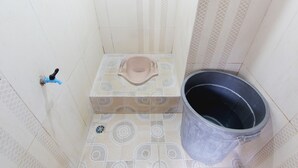 Un baño pequeño con inodoro, un cubo y un grifo.