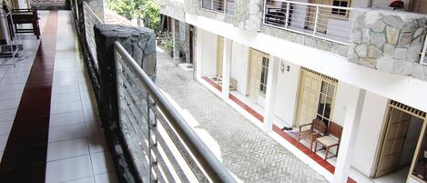 A multi-level building with a stone facade, a balcony with a metal railing, and a tiled floor.