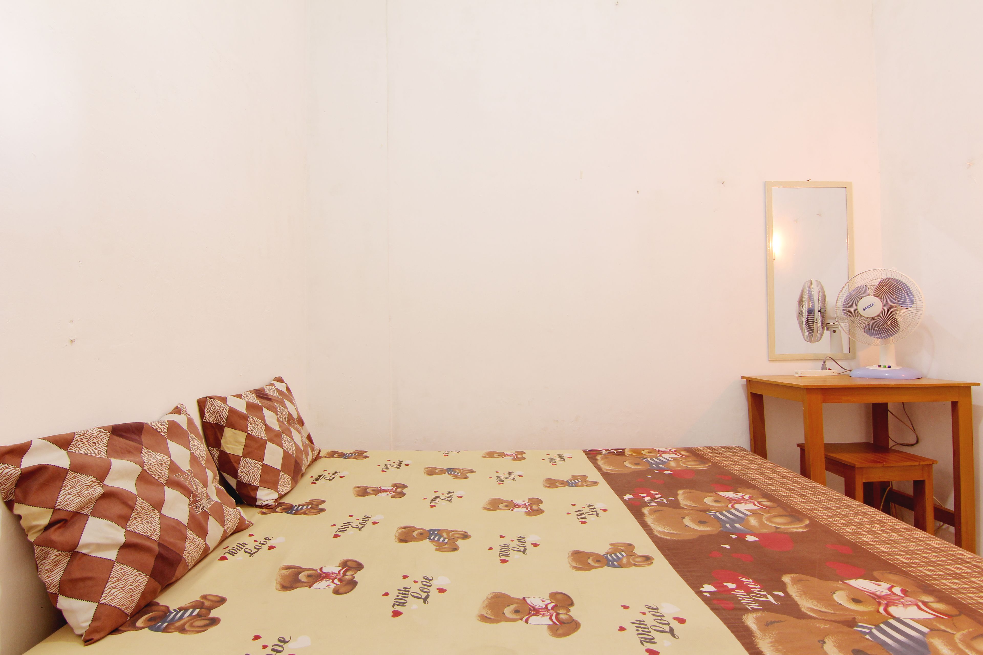 Un dormitorio con cama, almohadas, una mesita de noche y un espejo.