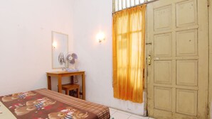 Un dormitorio con cama, escritorio, espejo y armario.