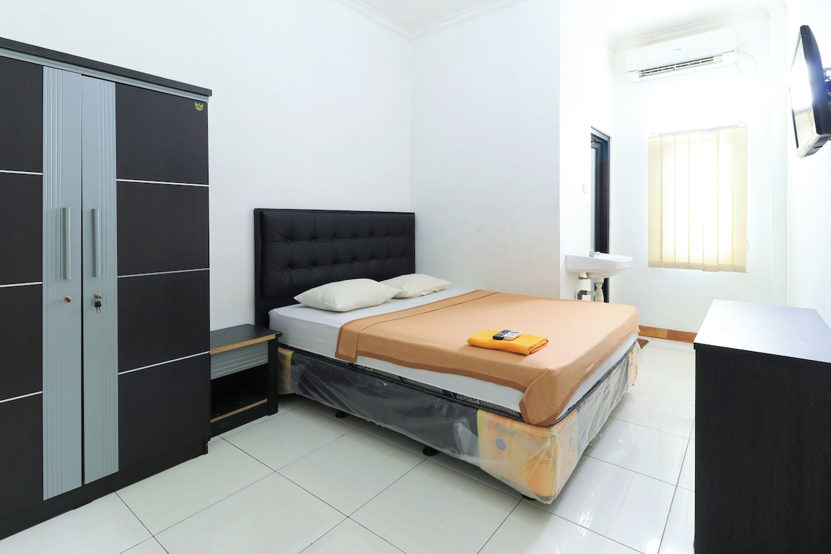 A bedroom with a bed, a wardrobe, a desk, and a window.