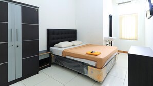 A bedroom with a bed, a wardrobe, a desk, and a window.