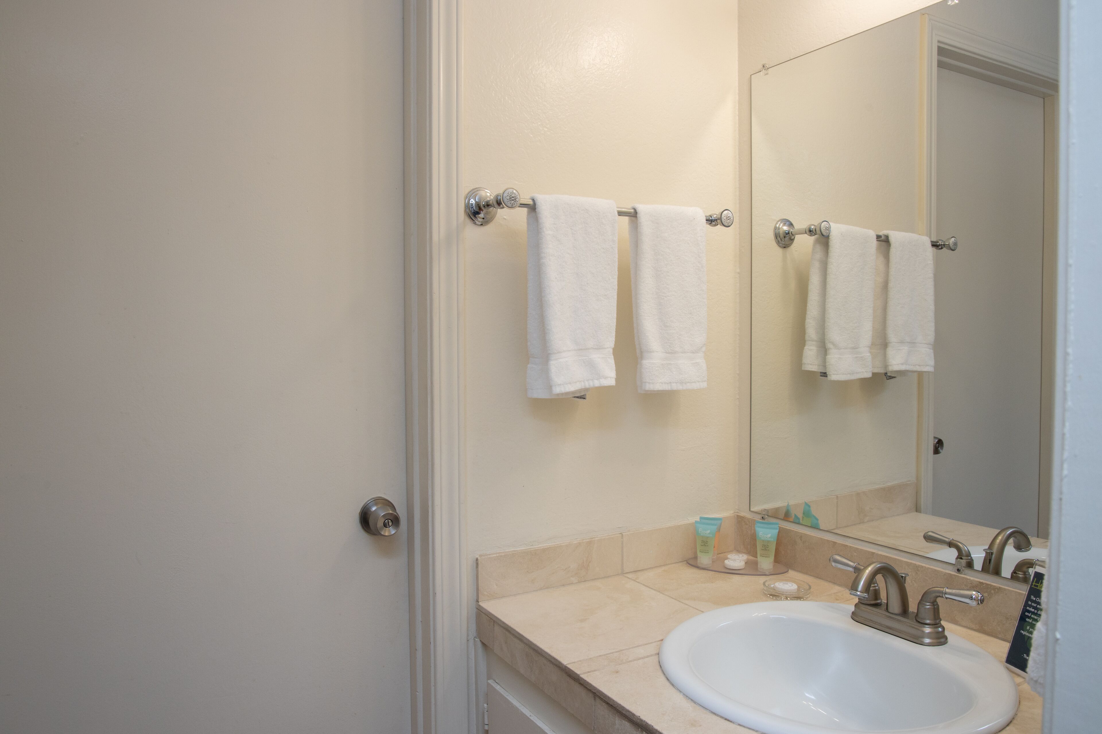 Une salle de bain avec un lavabo, un miroir et deux serviettes suspendues à un porte-serviettes.