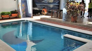 A swimming pool with tiled edges, surrounded by potted plants and a mural. - Casa Luna Hotel (Santa Marta)