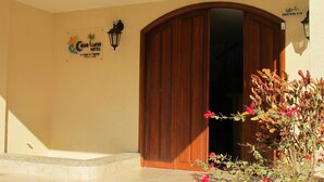A hotel entrance with a wooden door, a signboard, and a potted plant with flowers. - Casa Luna Hotel (Santa Marta)