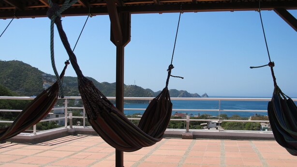 A hammock under a wooden pergola with a view of the sea and hills. - Casa Luna Hotel (Santa Marta)