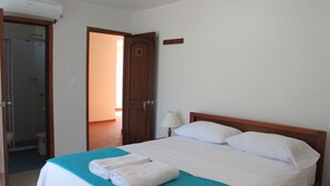 A hotel room with a bed, a bathroom door, and a hallway. - Casa Luna Hotel (Santa Marta)