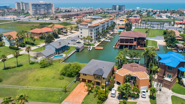 A coastal resort area with a marina, beachfront properties, and a variety of building styles. - Las Marinas #408 | Waterfront Condo • Boat Slip • 6 Minute Walk to Beach (South Padre Island)