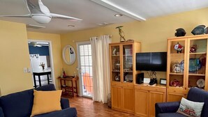 A living room with a blue sofa, a wooden cabinet with glass doors, and a television.