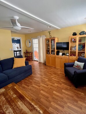Una sala de estar con un sofá azul, un mueble de madera con puertas de cristal y un televisor.