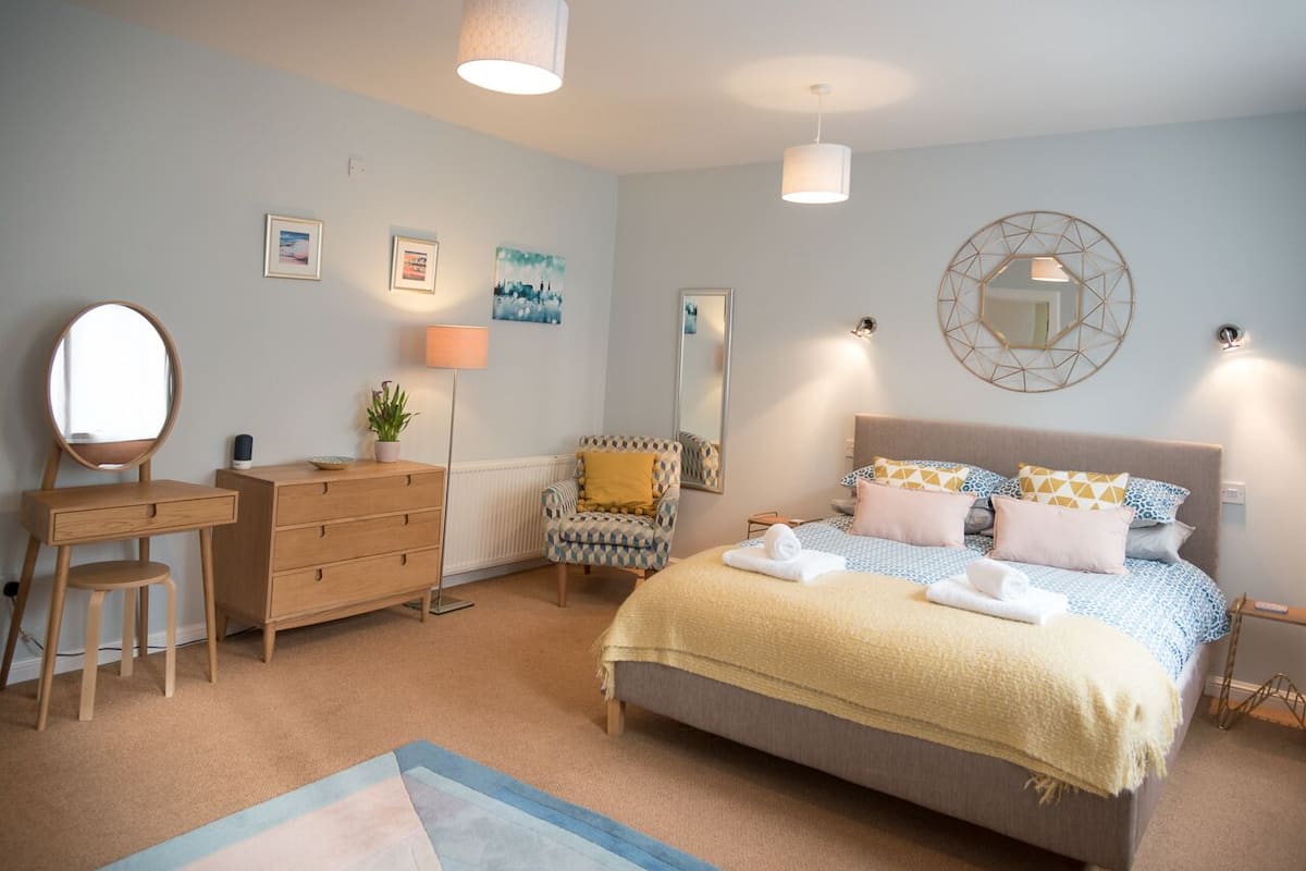 A bedroom with a bed, dresser, chair, and bedside tables.