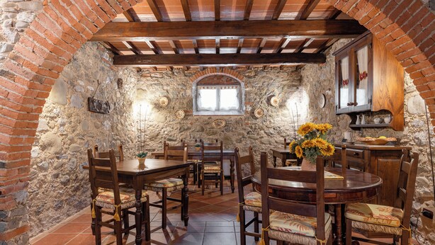 Un comedor rústico con paredes de ladrillo, mesas y sillas de madera.