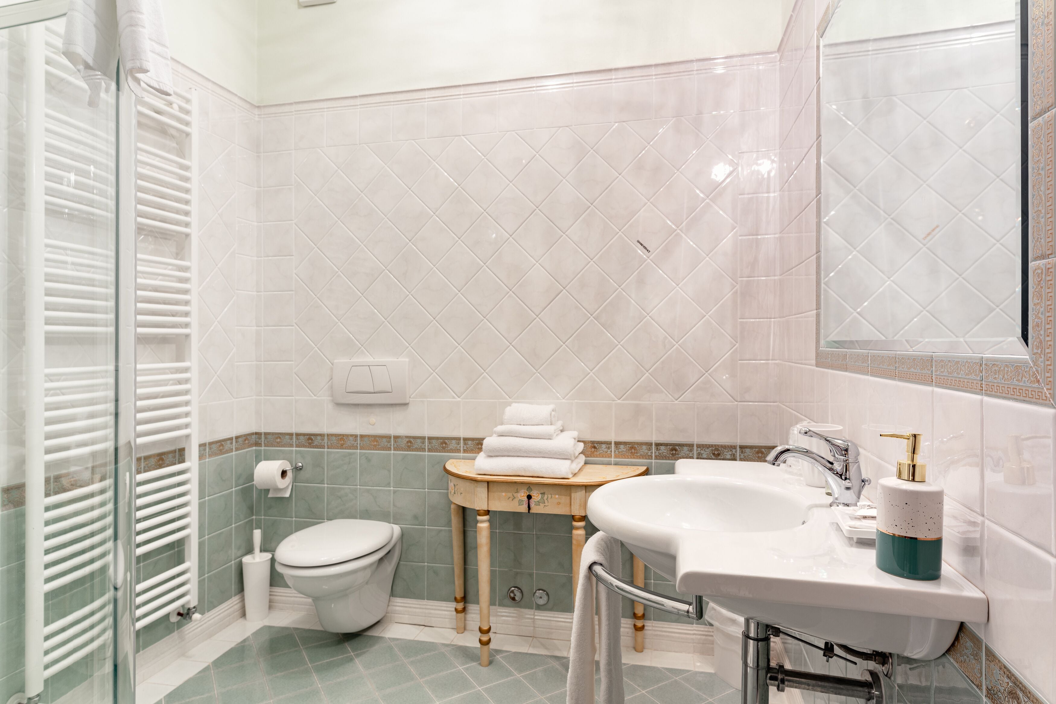 A bathroom with a toilet, sink, and glass shower enclosure.