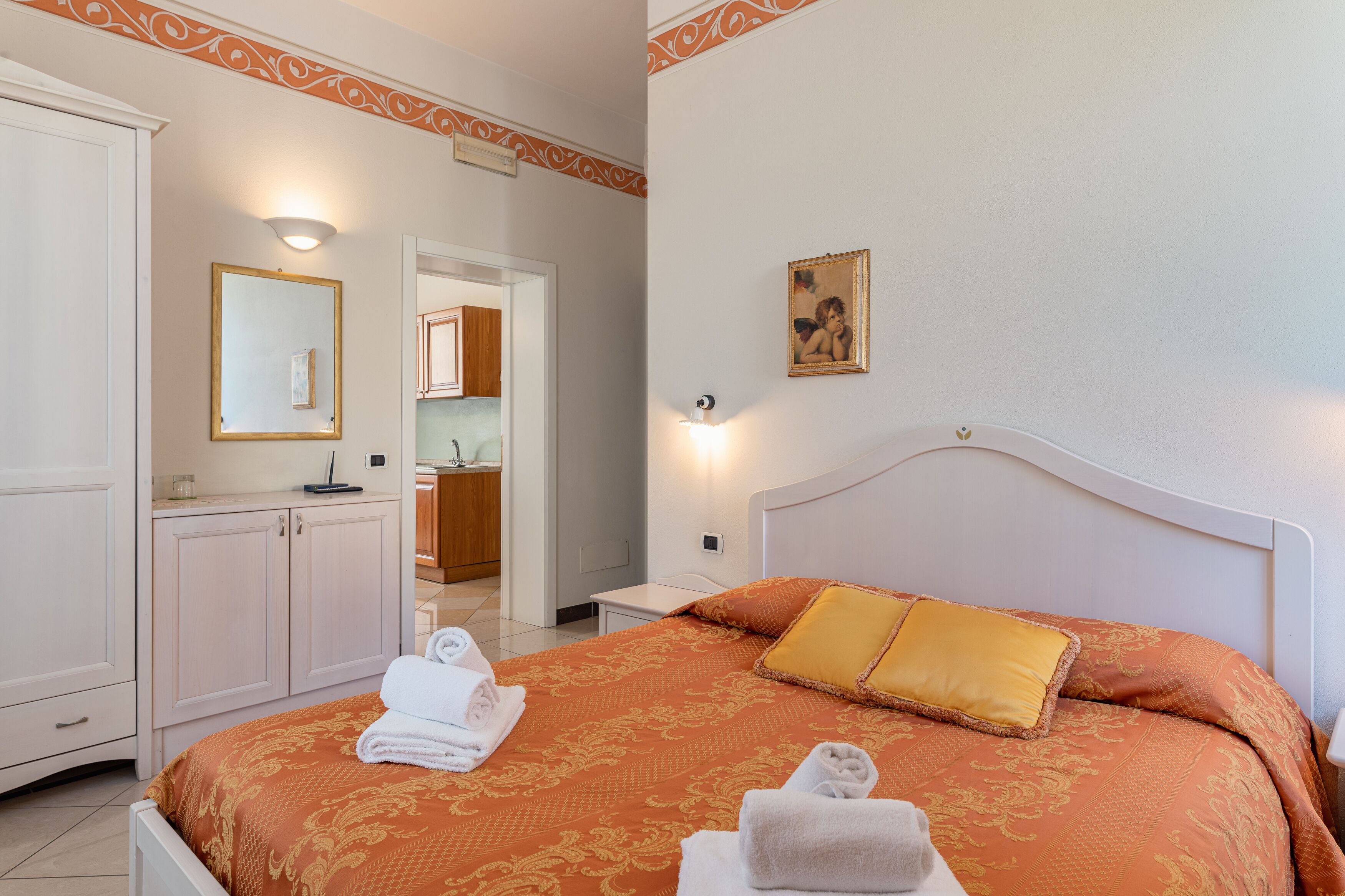 Quarto de hotel com cama, guarda-roupa, banheiro e espelho.