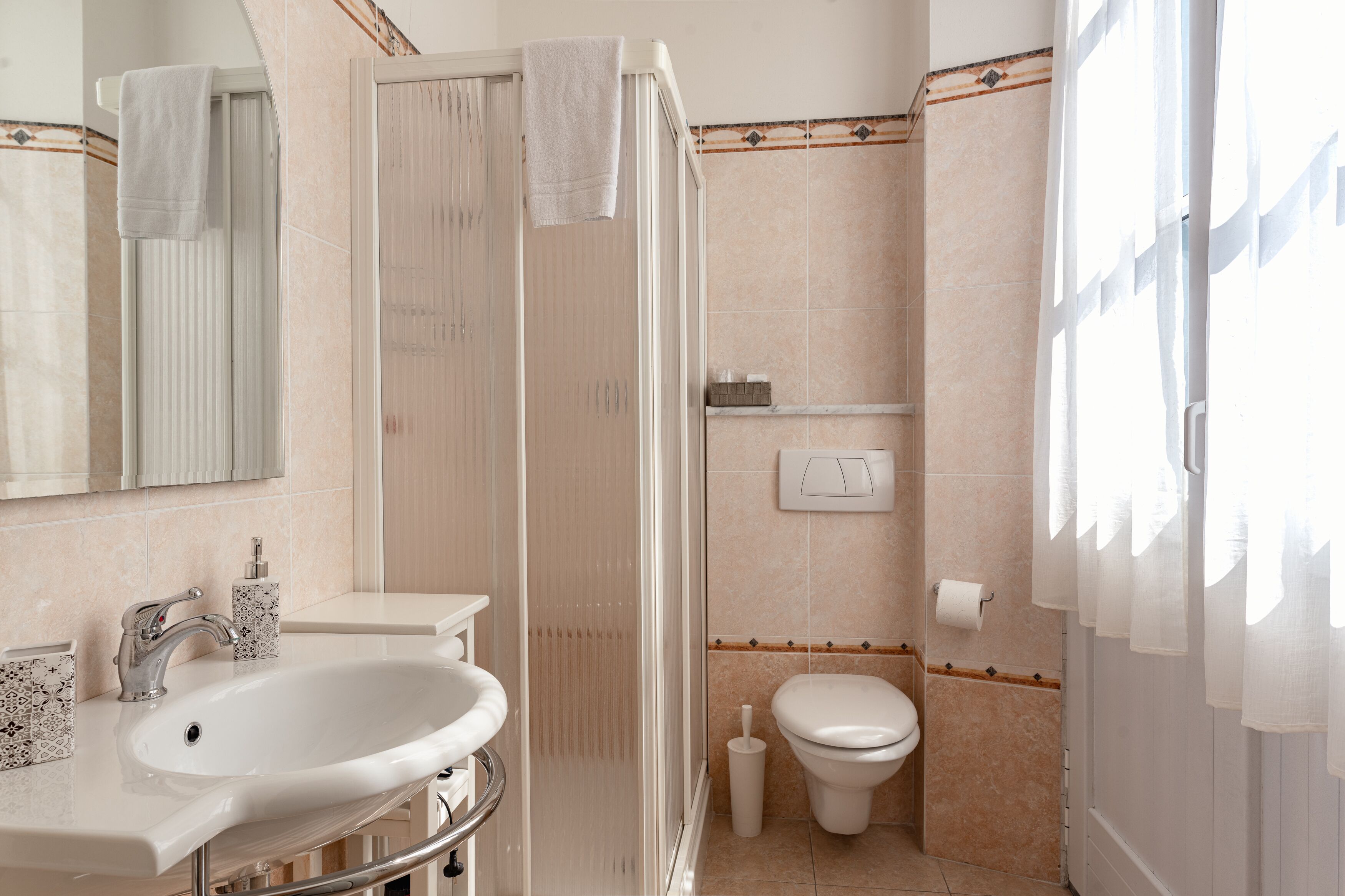 Une salle de bain équipée d’un lavabo, de toilettes, d’une douche et d’un miroir.