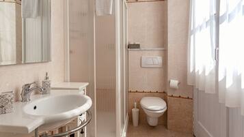 Une salle de bain équipée d’un lavabo, de toilettes, d’une douche et d’un miroir.