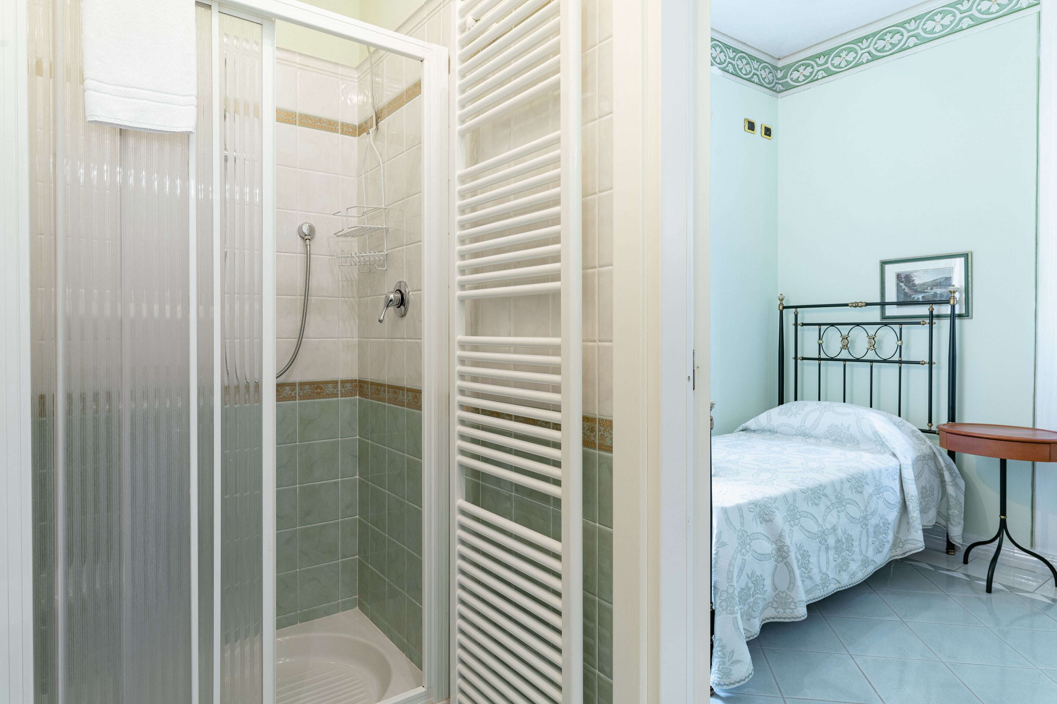 Een badkamer met een douche, een bed en een klein tafeltje.
