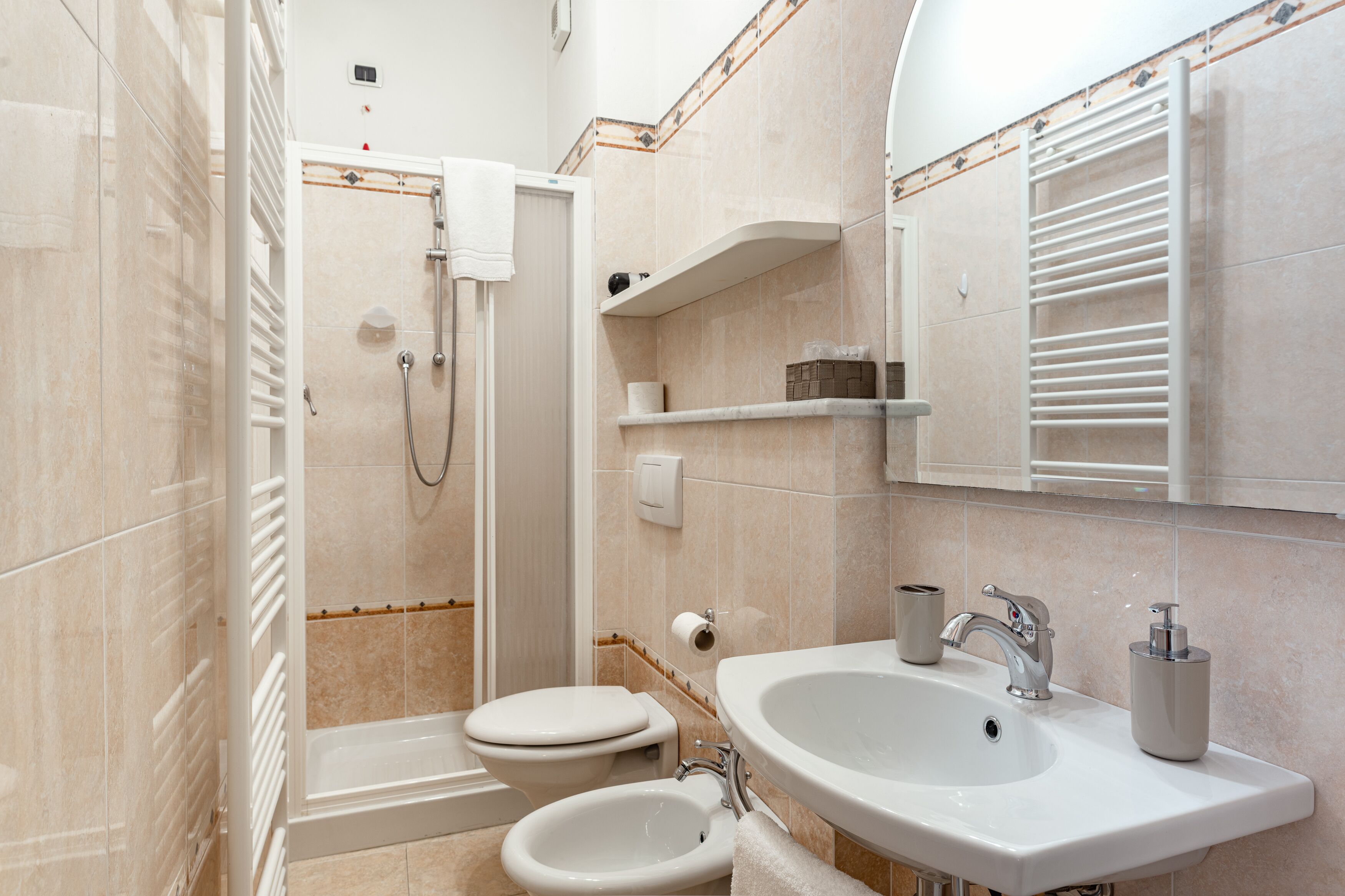 Un baño moderno con ducha, inodoro, bidé, lavamanos y espejo con toallero.