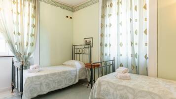 Quarto com duas camas de solteiro, uma mesinha e uma cadeira.
