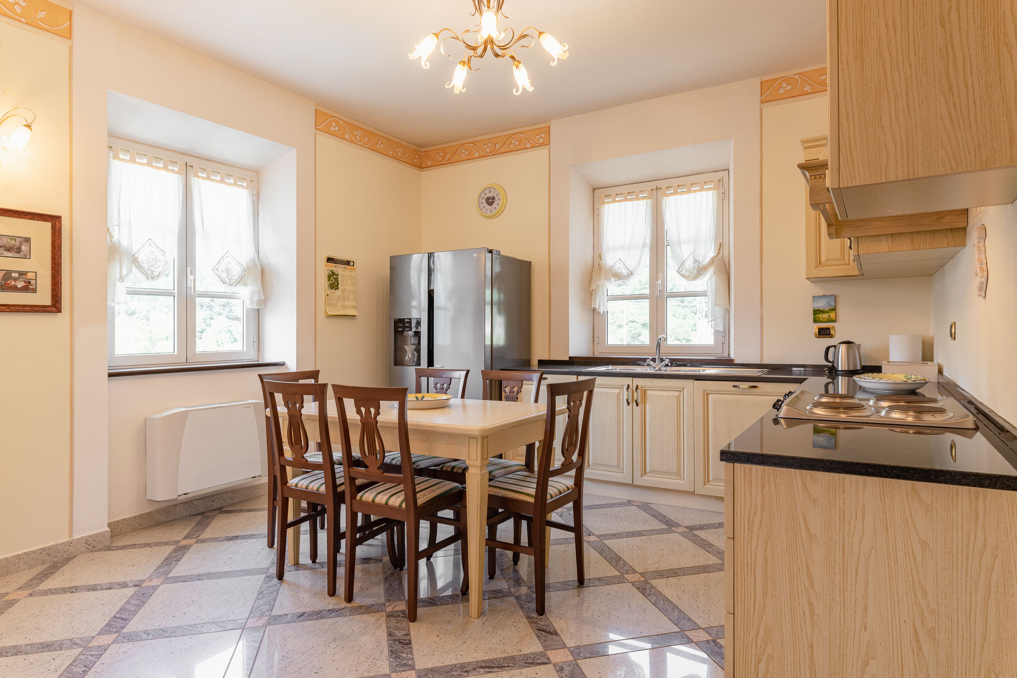 A kitchen with a dining table, chairs, a refrigerator, and a stove.