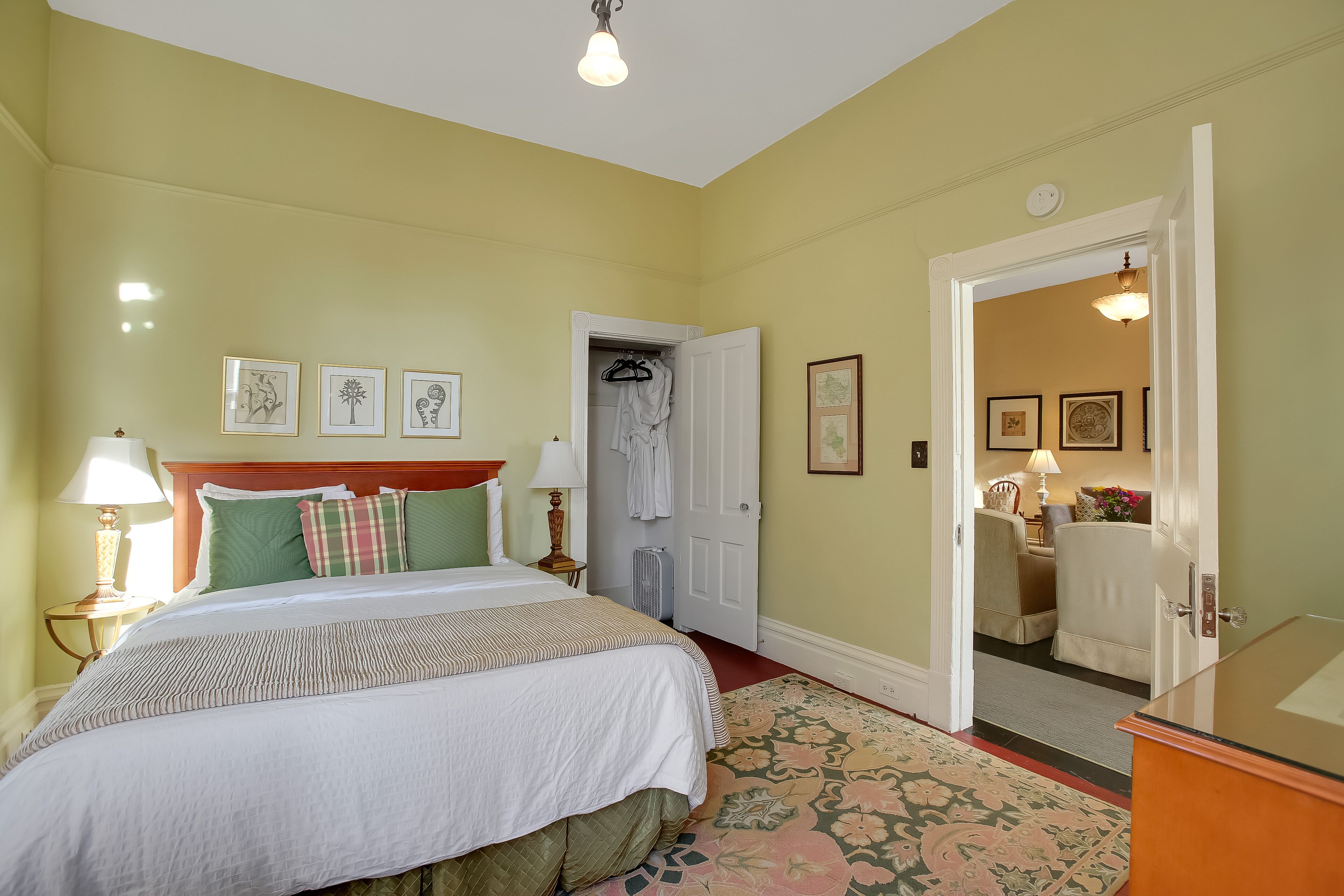 A neatly arranged bedroom with a bed, bedside tables, a wardrobe, and a mirror.