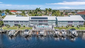 Un port de plaisance avec des bateaux amarrés, une piscine et un bâtiment doté d’un toit plat.