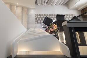 Staircase leads to an upper level with a dining area featuring a table for two and a vase of flowers.