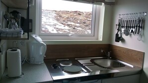 A kitchen with a window, stainless steel appliances, and a utensil rack. - Vatnsás 10 (Stykkisholmur)