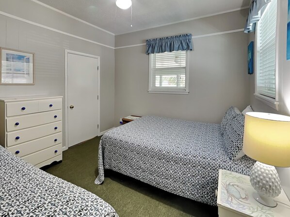 Un dormitorio con cama, cómoda, lámpara y ventana con persianas.