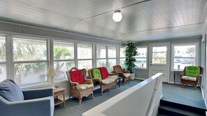 A sunlit room with wicker chairs, a blue sofa, and a staircase.