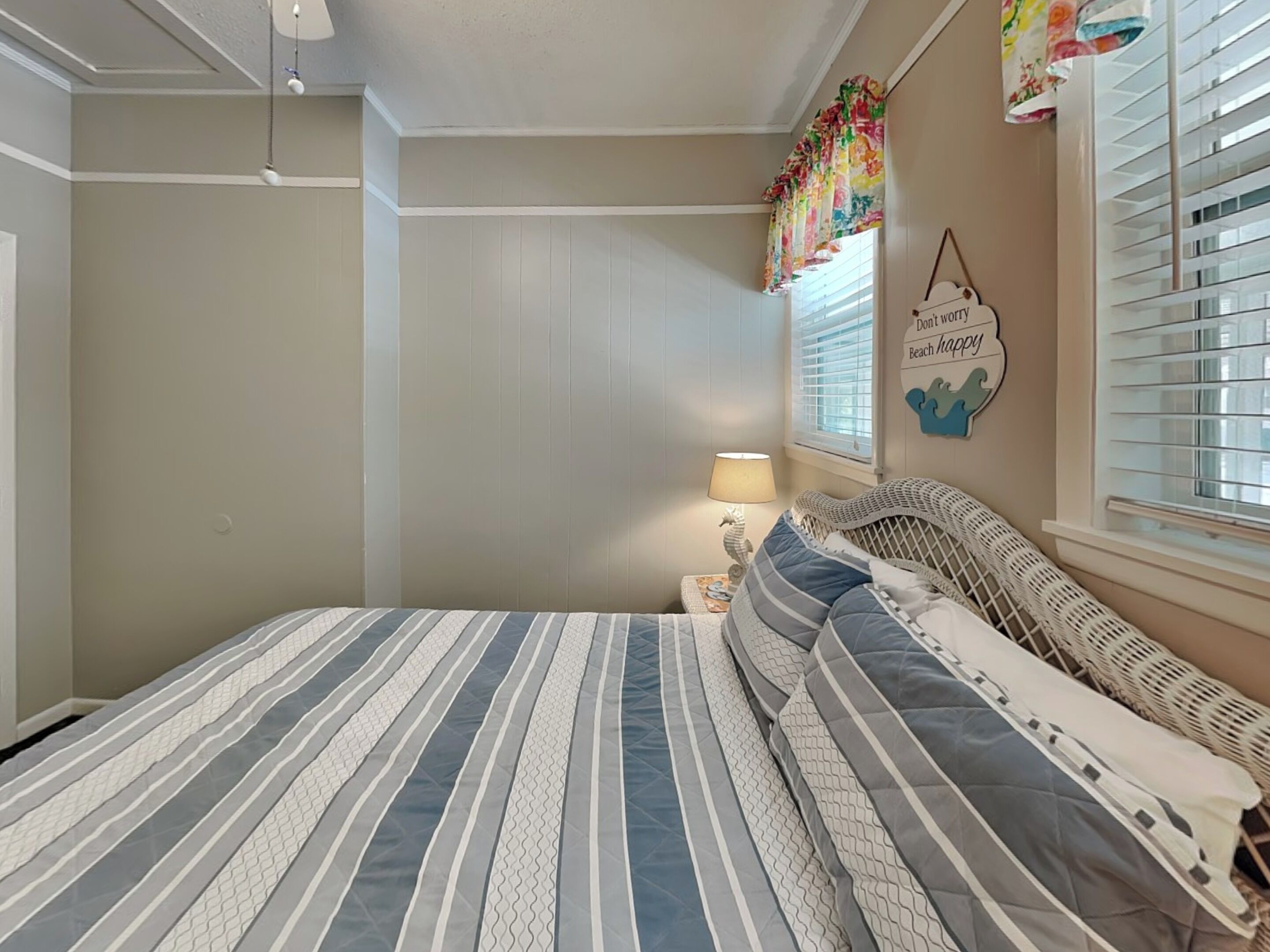 A bedroom with a striped bedspread, a bedside lamp, and a wall decoration.