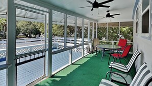 A covered outdoor area with a green floor, white railings, and a table with chairs.