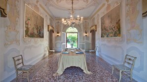 Una habitación opulenta con una gran mesa, sillas ornamentadas y un candelabro.