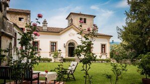 Un edificio histórico con un patio, una mesa con un florero y una estatua en el tejado.
