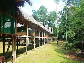 A wooden structure with thatched roofs, supported by wooden stilts, in a forested area. - Yanayacu River Lodge (Indiana)