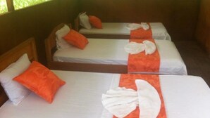Três camas de solteiro com roupa de cama branca e laranja, dispostas em fila.