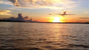 Um pôr do sol sobre a água, com nuvens refletidas na superfície.