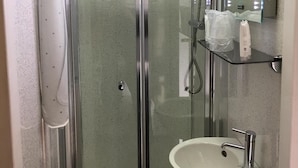 Un bany modern amb dutxa de vidre, un envàs de color blanc i un mirall amb llums LED.