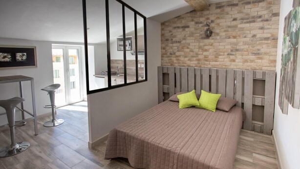 Une chambre à coucher avec un lit, une tête de lit en bois, un mur en briques et une fenêtre.