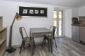 Een eethoek met een tafel en stoelen, een vloerlamp en een kunstwerk in een lijst erboven.