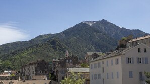 Un paysage montagneux avec, au premier plan, une ville historique caractérisée par son architecture traditionnelle et un clocher d’église imposant.