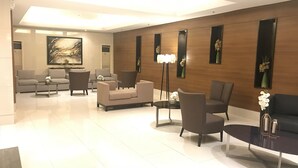 En moderne lobby med sofa, stole, sofabord og gulvlampe.