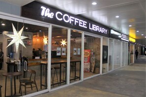 Step into The Coffee Library, a welcoming coffee shop with a modern design, featuring large windows and a casual dining area.
