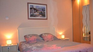 Une chambre à coucher avec un lit, deux lampes de chevet, une table de chevet, un tableau au mur et un miroir au mur.