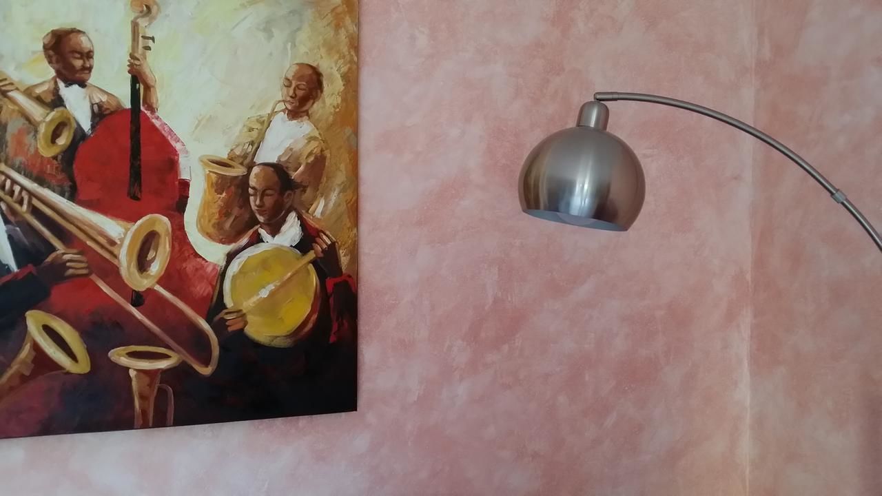 A painting of musicians on a wall with a modern floor lamp.