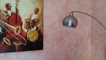 Un dipinto di musicisti su una parete, illuminata da una lampada da terra moderna.