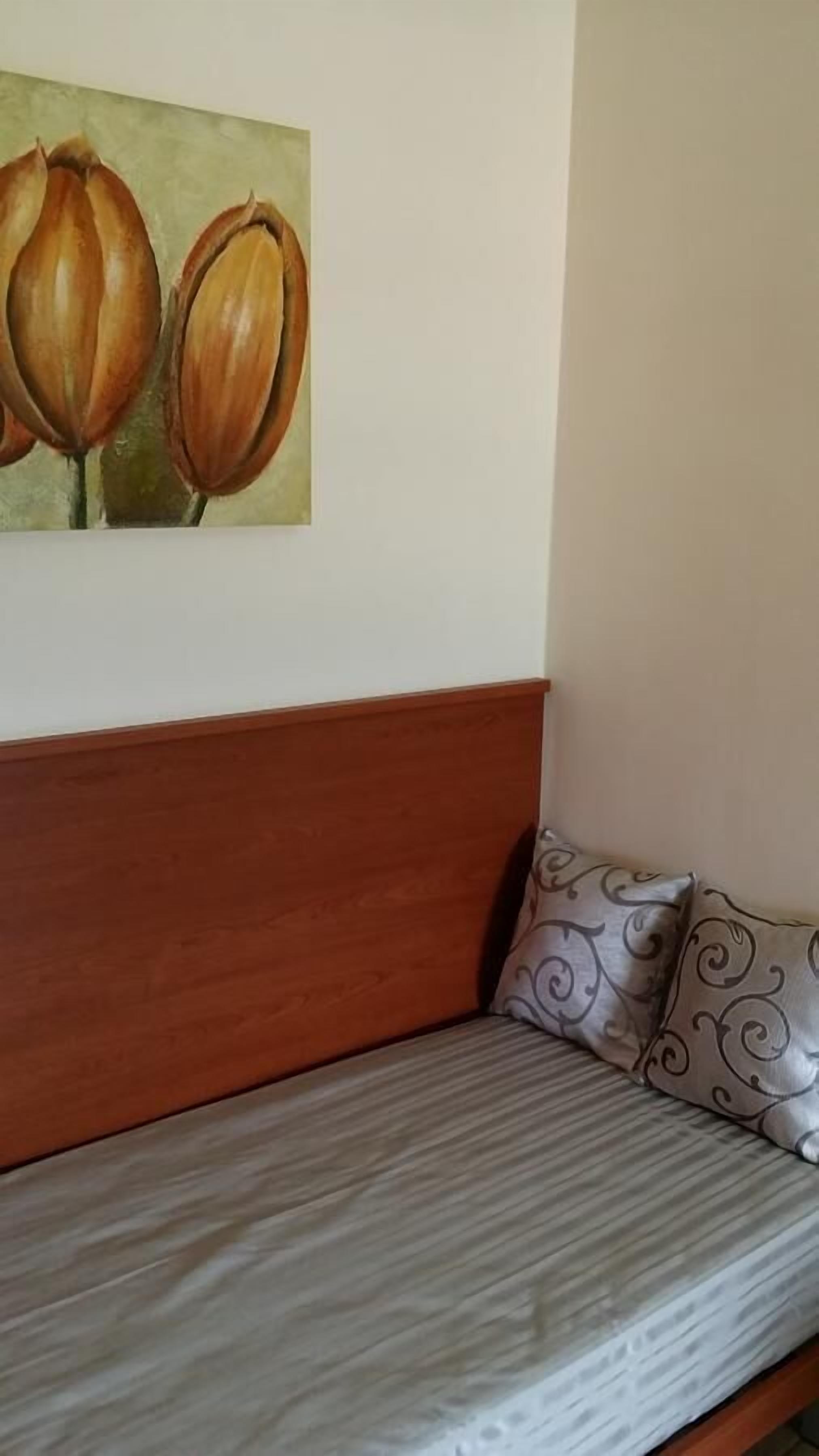 A room with a wooden headboard, a gray striped sofa, and a pillow with a swirl pattern.