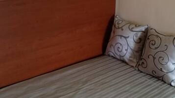 A room with a wooden headboard, a gray striped sofa, and a pillow with a swirl pattern.