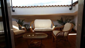 A balcony with wicker furniture, including two chairs and a table, and potted plants. - Il Tulipano (Rogliano)