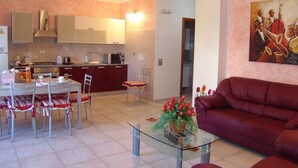 A modern living room with a red sofa, a glass coffee table, and a dining area with a table and chairs. - Il Tulipano (Rogliano)